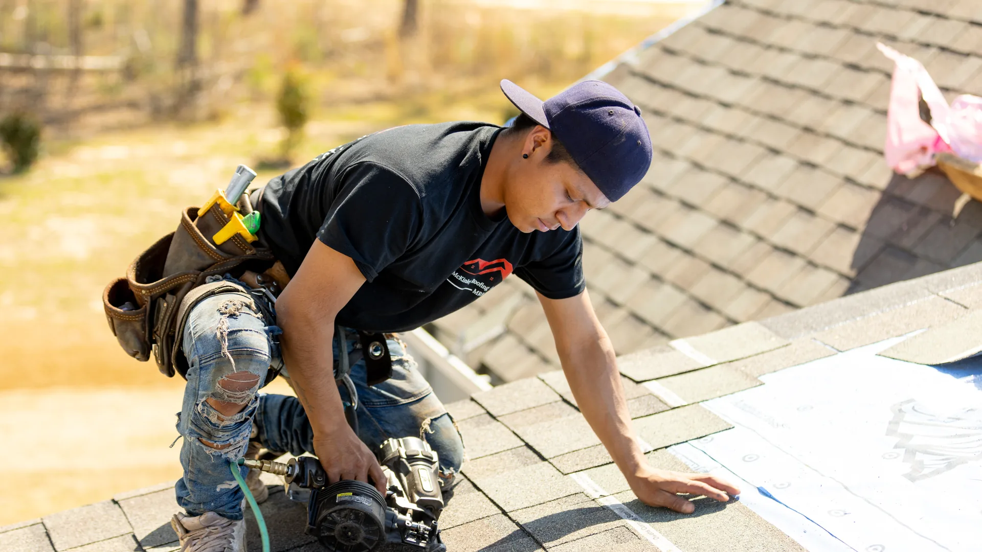 A McKinley Roofing crew member working on an asphalt shingle roof